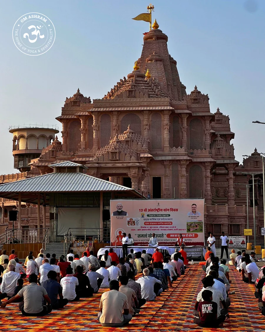 Over 200 people practicing yoga together in front of the grand Shiva Temple at OM